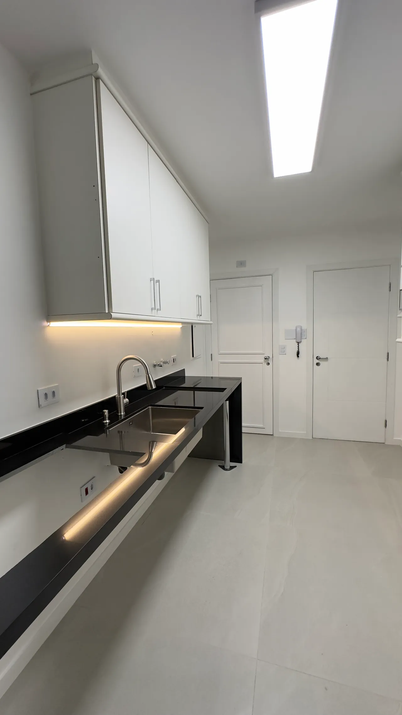 Cozinha minimalista com bancada preta e marcenaria branca